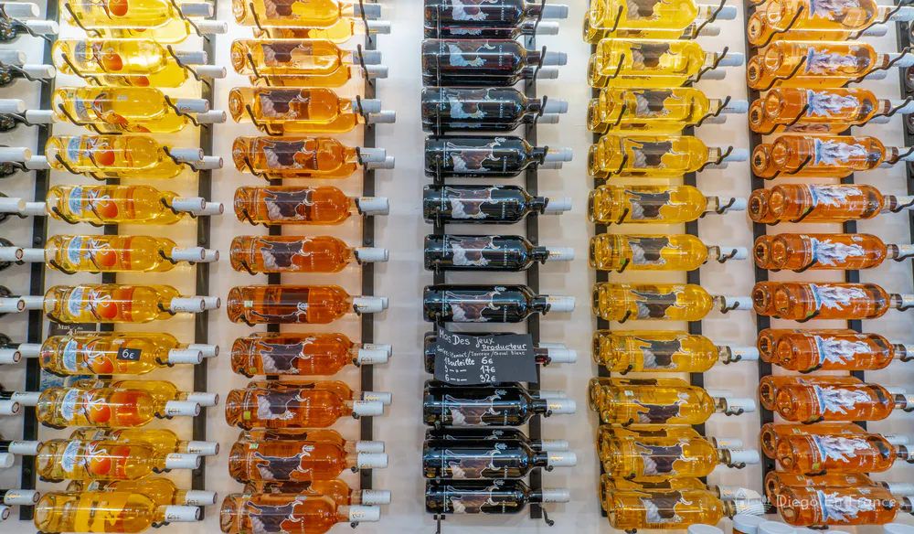 Exhibición de botellas de vino de colores vibrantes en Aigues-Mortes, reflejo de la rica viticultura local. Fotografía de diegoenfrance.com