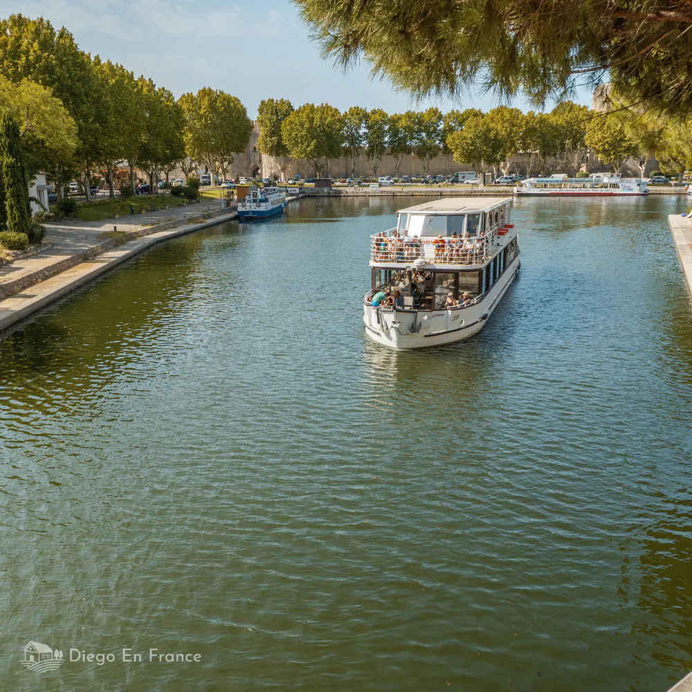 Barco turístico navegando por el canal que bordea las murallas de Aigues-Mortes. Fotografía de diegoenfrance.com