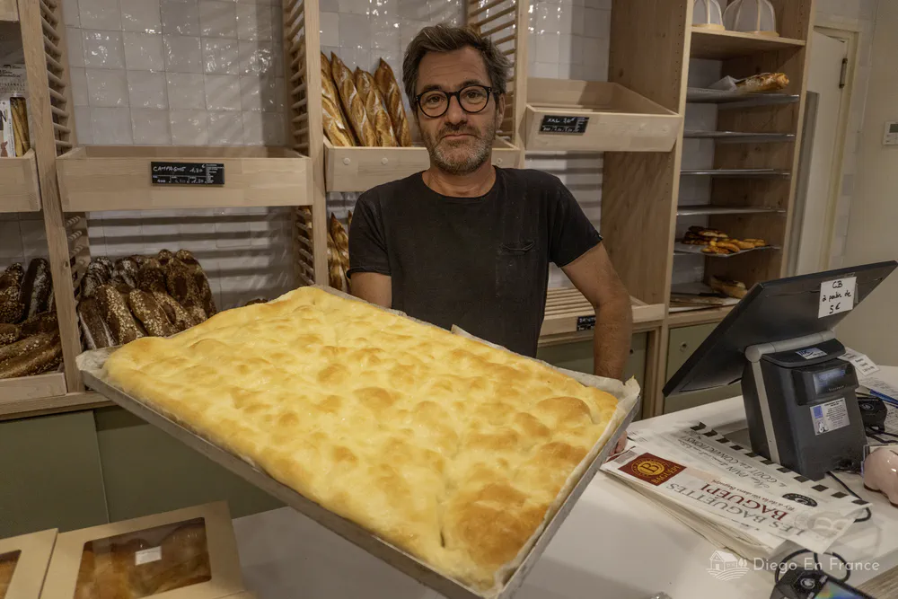 Panadero mostrando una fougasse recién salida del horno, en una panadería artesanal del centro. Fotografía de diegoenfrance.com