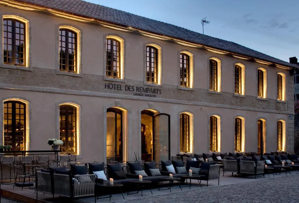 Fachada iluminada al anochecer del Hôtel des Remparts, un refugio sofisticado en el casco histórico