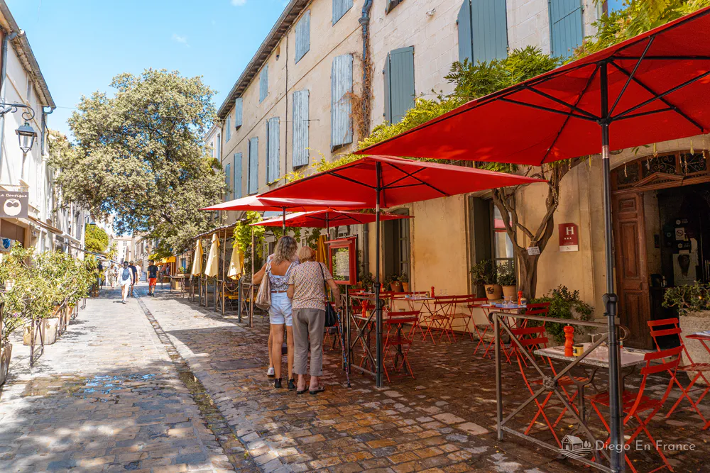 Fotografía de diegoenfrance.com: restaurante con terrazas rojas y calles empedradas dentro de las murallas de Aigues-Mortes.