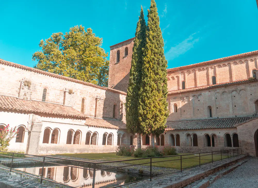 Claustro de la abadía con arcos de piedra y ciprés central