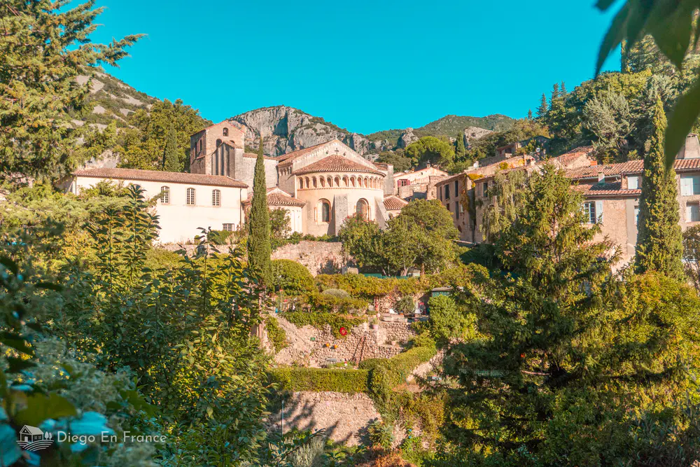 Vista general de la abadía y casas del pueblo rodeadas de vegetación mediterránea