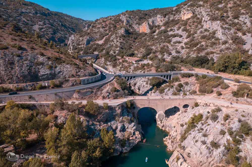 Le Pont du Diable sobre río turquesa entre gargantas rocosas y carreteras del valle del Hérault.