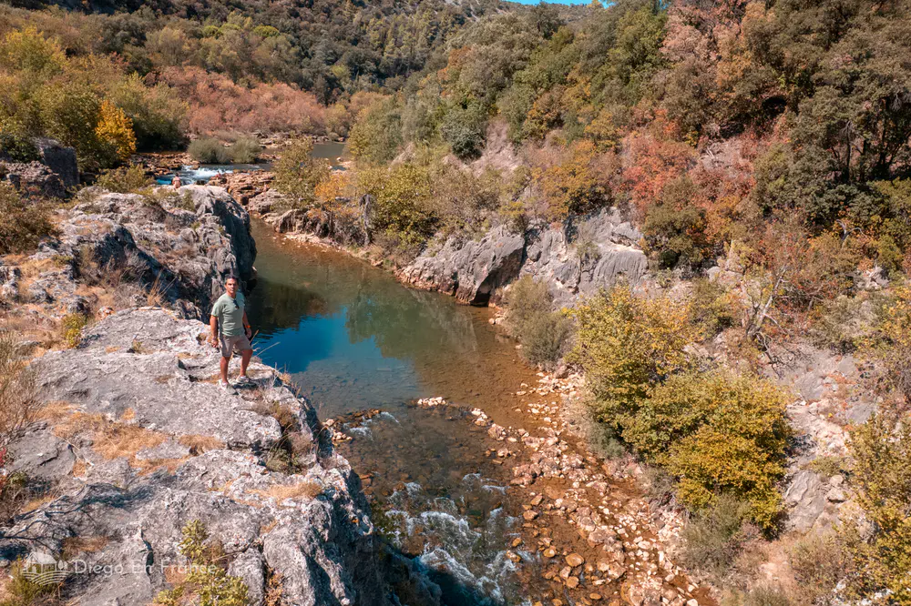 Río estrecho entre rocas y vegetación con persona observando desde la orilla