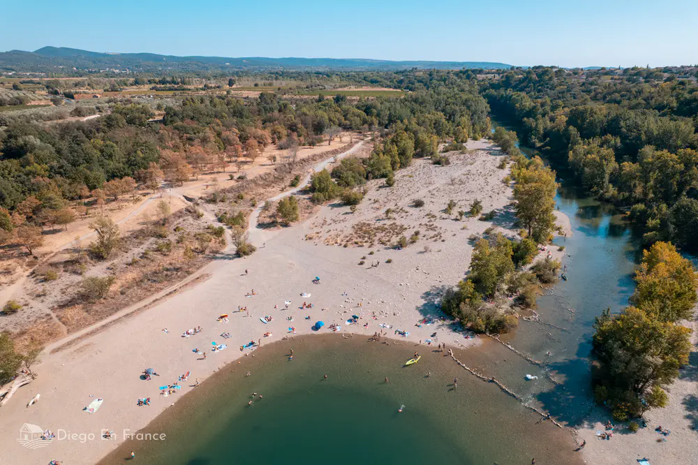 Playa fluvial amplia con personas bañándose junto al río Hérault