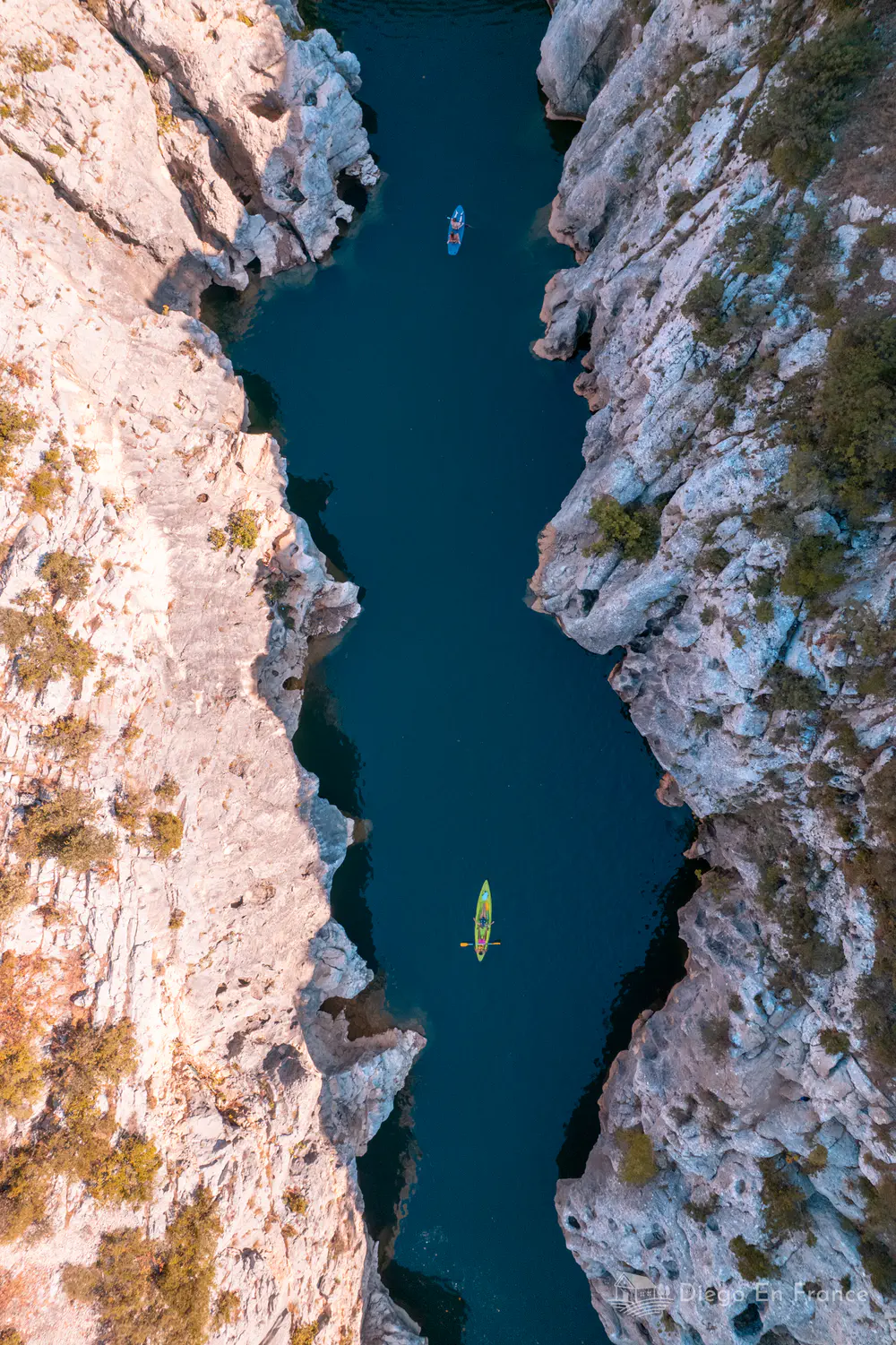 Vista aérea de río encajado entre gargantas rocosas con personas en kayak