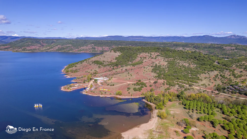 Vista aérea del lago del Salagou con aguas azules y terreno rojizo alrededor