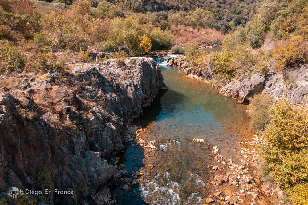 Río tranquilo encajado entre rocas y vegetación otoñal cerca de Saint-Guilhem-le-Désert
