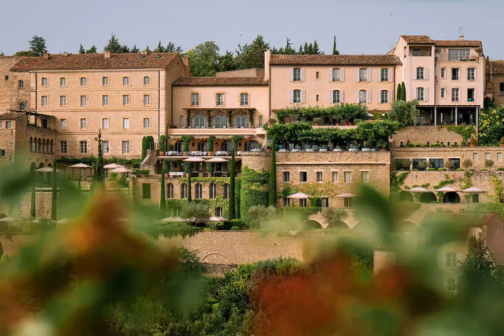 Fotografía de la fachada del hotel La Bastide de Gordes, rodeado de vegetación y terrazas