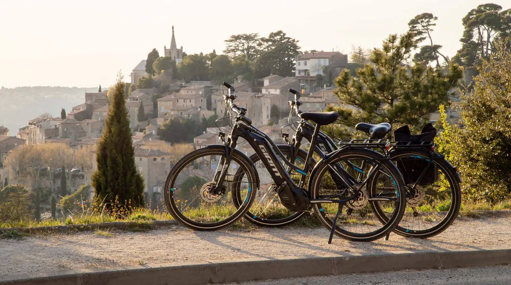 Fotografía de diegoenfrance.com de bicicletas eléctricas aparcadas con el pueblo de Gordes al fondo