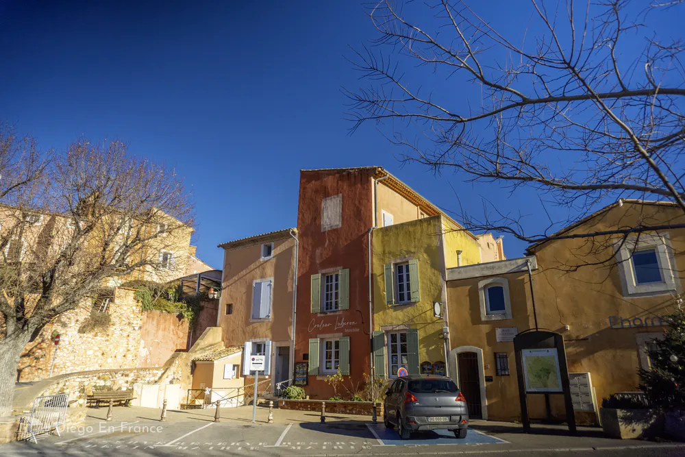 Fotografía de diegoenfrance.com de las fachadas ocre, roja y amarilla que caracterizan la entrada a Roussillon desde el aparcamiento principal