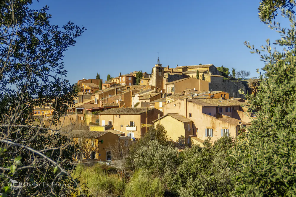 Fotografía de diegoenfrance.com del pueblo de Roussillon visto entre los árboles, ideal para ilustrar rutas y actividades que hacer en Roussillon, Francia