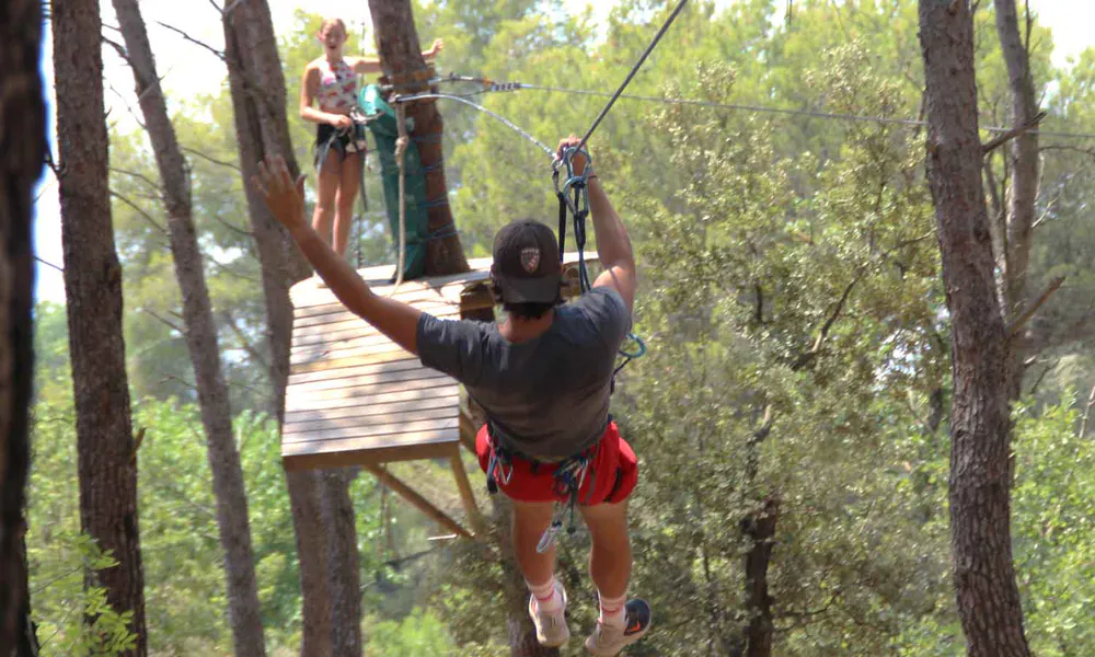 Fotografía de un adulto en tirolina en un bosque del Vaucluse, parque de aventuras
