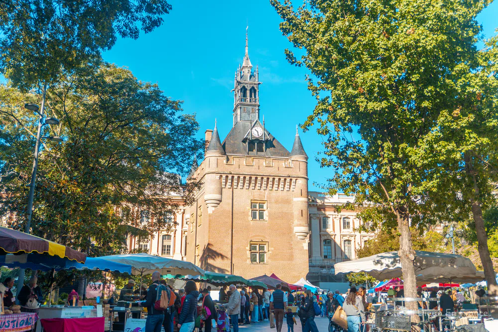 Fotografía de diegoenfrance.com mostrando el Donjon du Capitole y su entorno lleno de puestos y visitantes en el corazón de Toulouse.