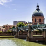 Vista de Toulouse un dia soleado con un hermoso puente sobre el rio y sus cupulas de fondo