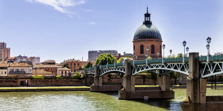 Vista de Toulouse un dia soleado con un hermoso puente sobre el rio y sus cupulas de fondo