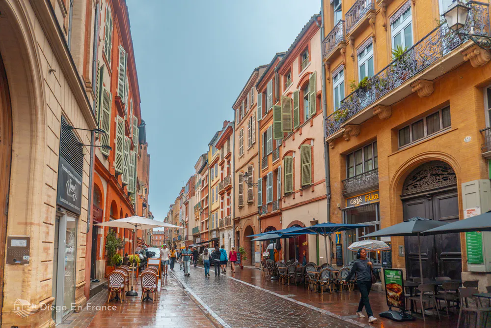 Photo de diegoenfrance.com montrant une rue piétonne avec des cafés et des bâtiments historiques dans le centre de Toulouse.