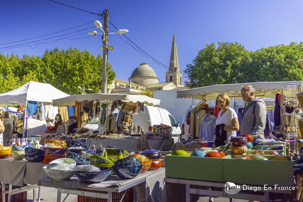 Mercado al aire libre con puestos de cerámica y productos artesanales frente a una iglesia histórica. Fotografía de diegoenfrance.com