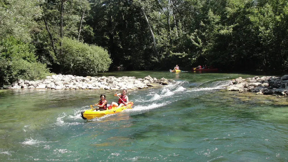 Personas navegando en canoas sobre aguas cristalinas rodeadas de naturaleza.