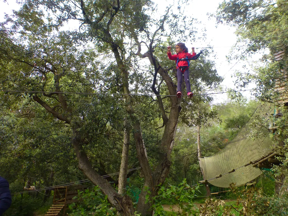 Niña atravesando un puente colgante en un parque de aventura en los bosques de la Provenza. Fotografía de diegoenfrance.com