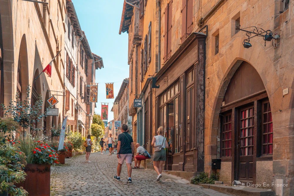 Calle empedrada con visitantes y edificios históricos de piedra