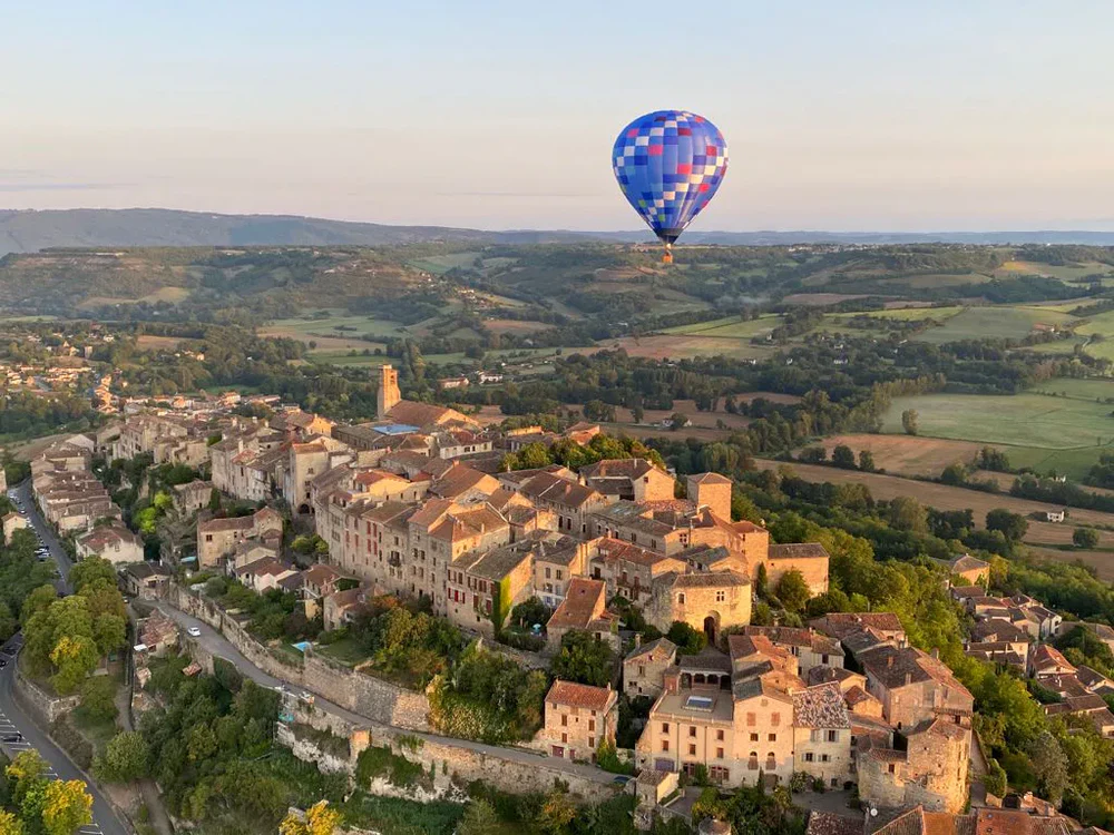 Globo aerostático sobre pueblo medieval y campos rurales