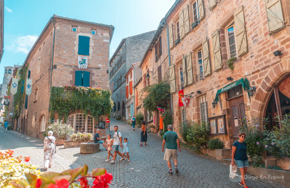Plaza empedrada con casas de piedra y visitantes