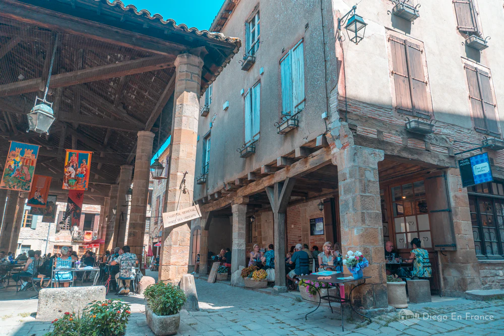 Soportales de madera con terrazas y mesas en Cordes-sur-Ciel