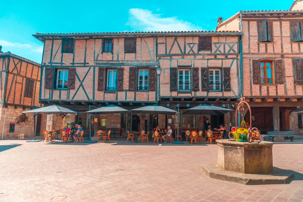 Ambiente relajado en la Place des Arcades, corazón del pueblo medieval