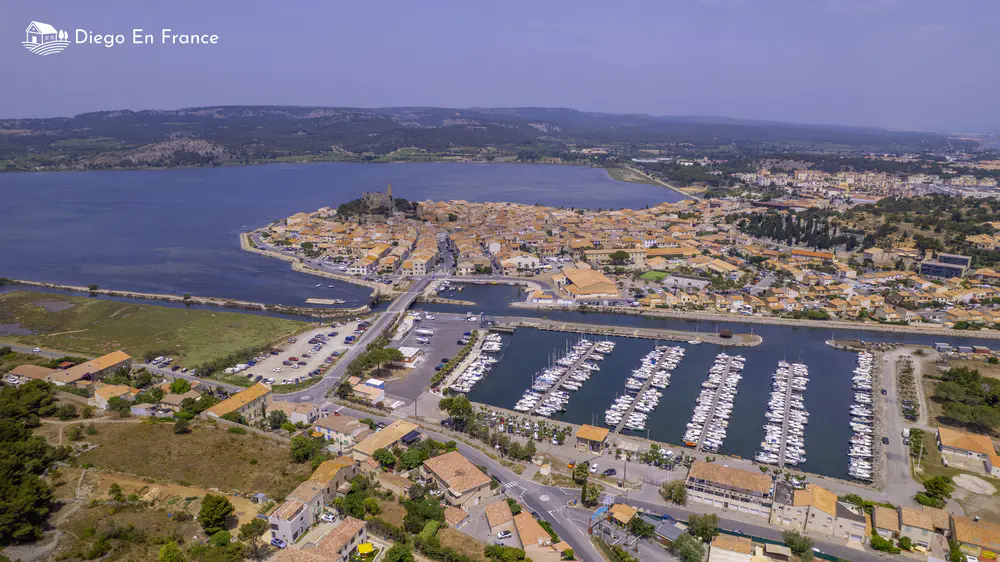 Coastal village surrounded by lagoons, a marina, and light-roofed houses by the sea.