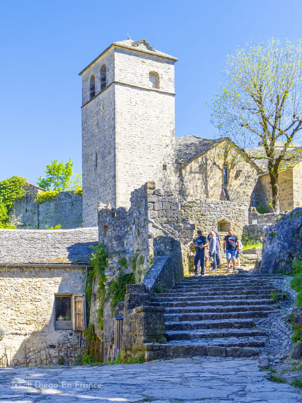 Cobblestone street with stone houses and medieval towers in a village in southern France