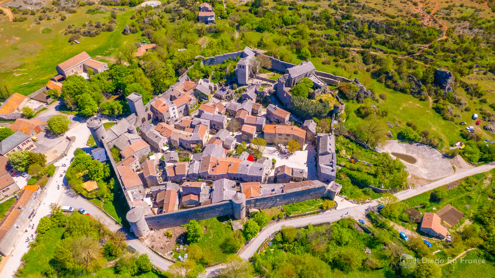 Aerial view of a walled village surrounded by fields and hills in southern France