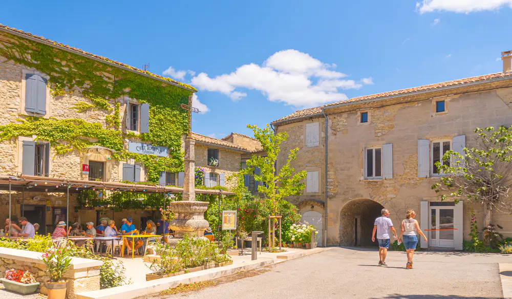 Square with terraces, trees, and stone buildings in a village in the south of France