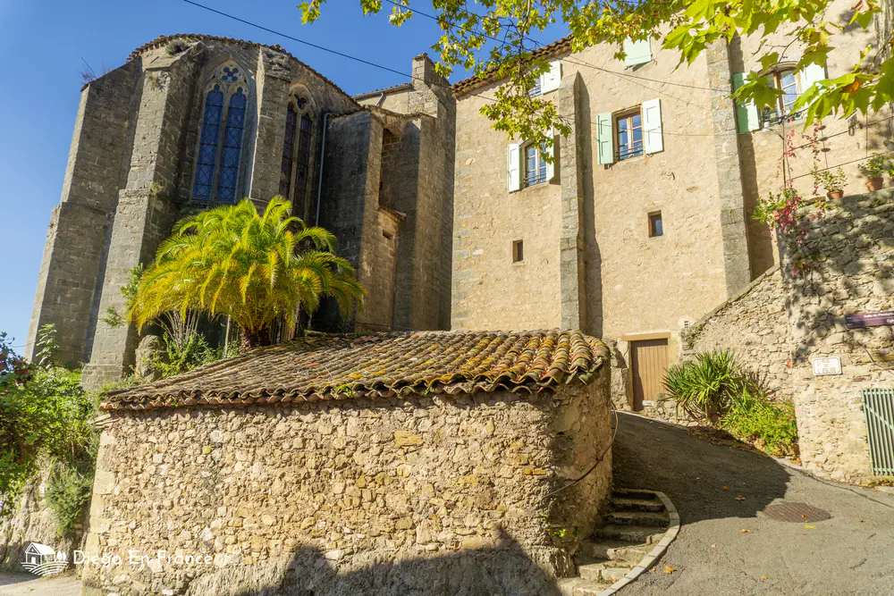 Stone building next to a church with a palm tree and an ascending path