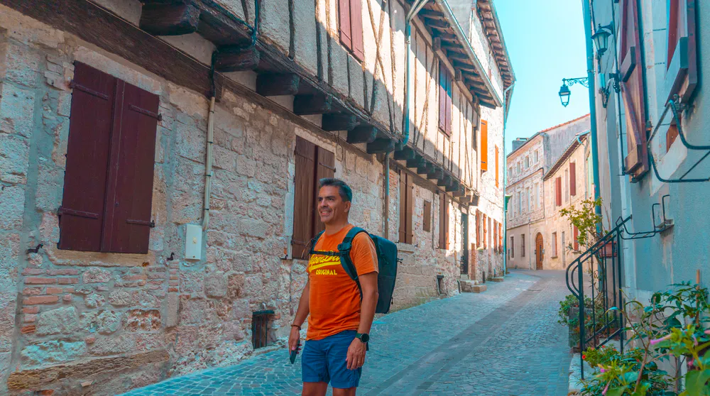 Tourist walking through the little streets of Castelnau-de-Montmiral, discovering its charm.