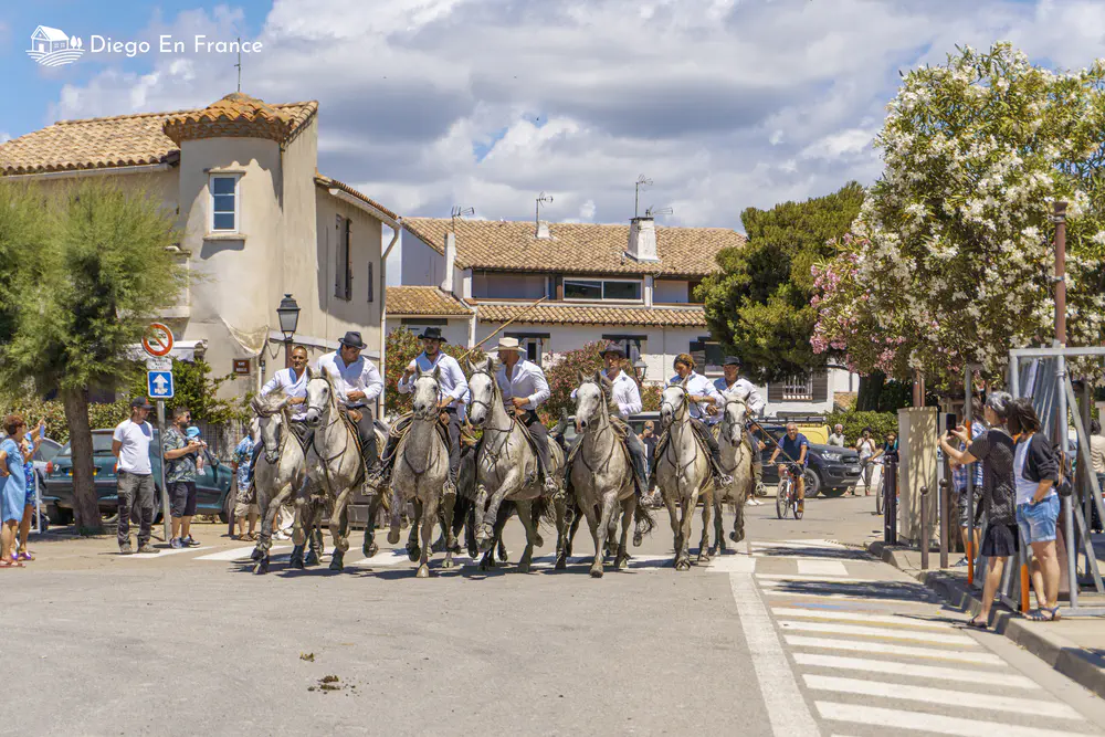 Horsemen parading down a street lined with spectators and low buildings