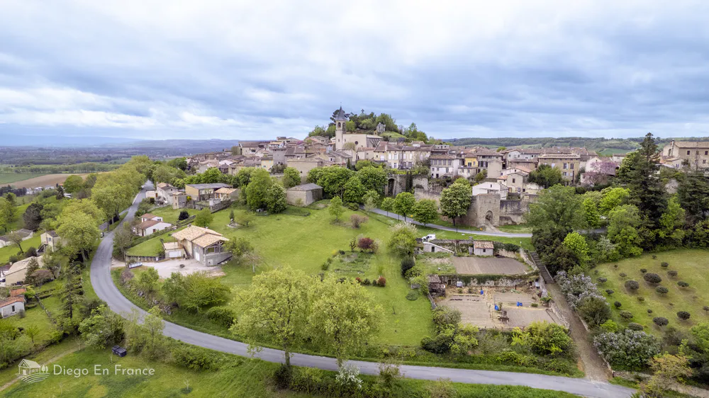 Medieval village surrounded by green fields and rural roads on a hill in southern France