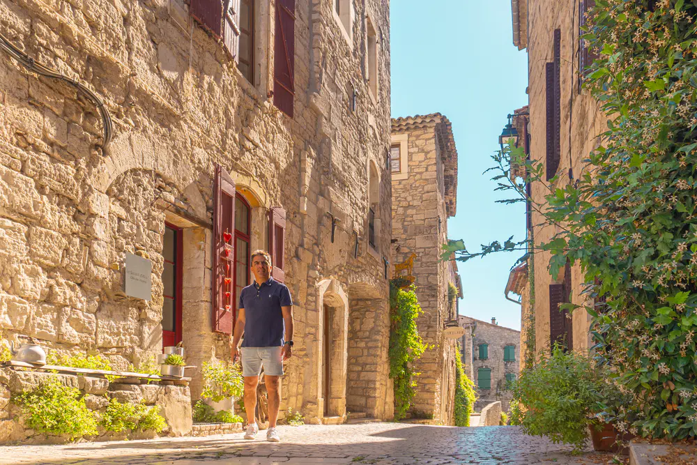 Narrow street with stone houses and a person walking in a medieval village in southern France
