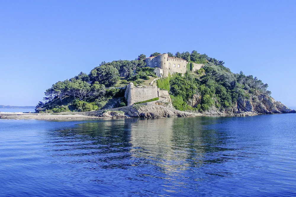 Isla rocosa con fortaleza histórica rodeada de aguas tranquilas del mar Mediterráneo