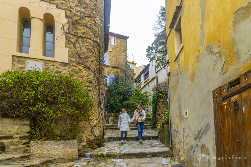 Calle empedrada del casco antiguo con dos personas caminando entre fachadas de piedra