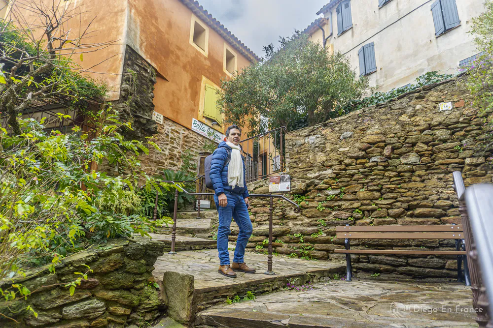 Hombre de pie en un rellano de escaleras de piedra entre muros antiguos del casco histórico