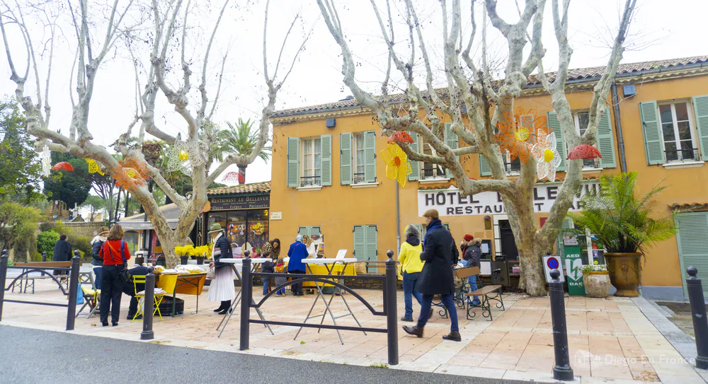 Plaza del pueblo con puestos de mercado y edificio tradicional de fachada ocre