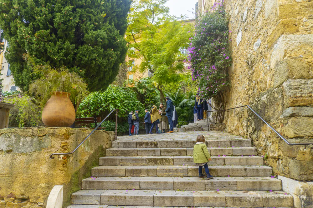 Escalinata de piedra en el casco antiguo con visitantes y niño subiendo los peldaños