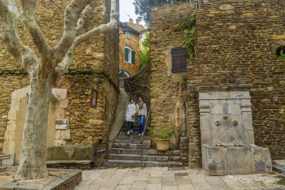 Escaleras estrechas entre muros de piedra con dos personas descendiendo