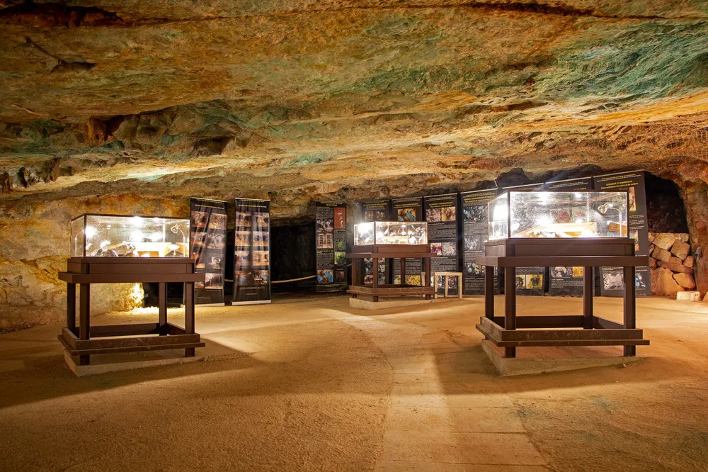 Sala subterránea con vitrinas iluminadas y paneles informativos dentro de una antigua mina