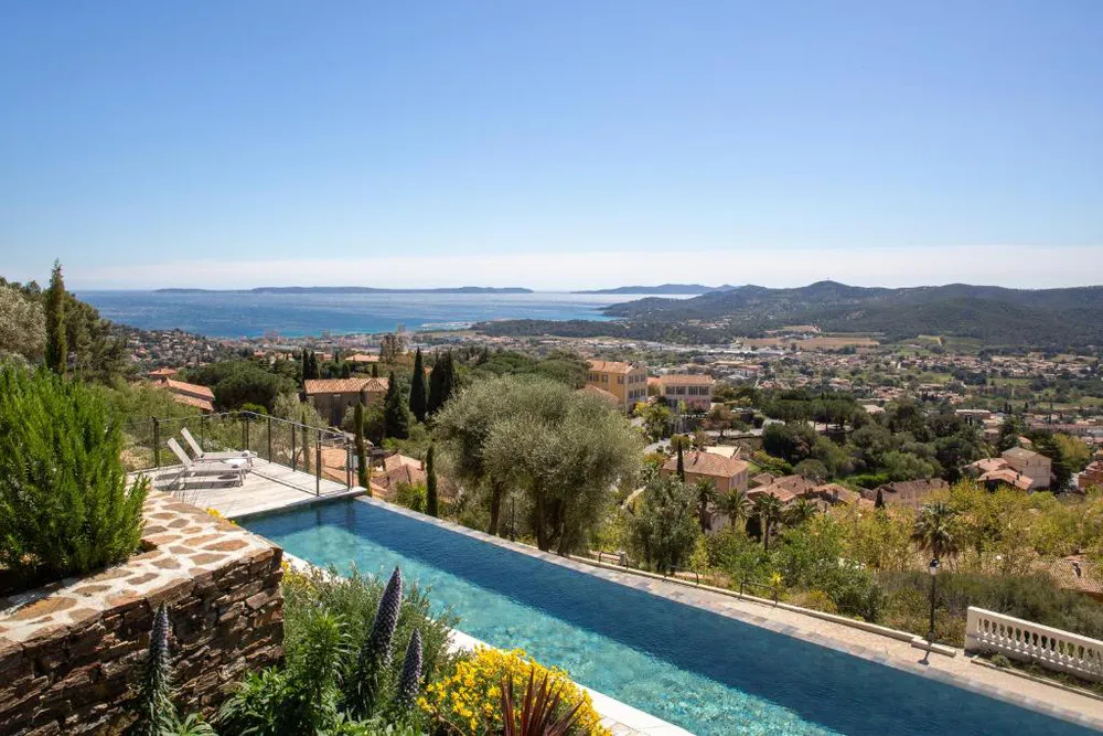 Piscina al aire libre con vistas al mar, colinas y viviendas dispersas