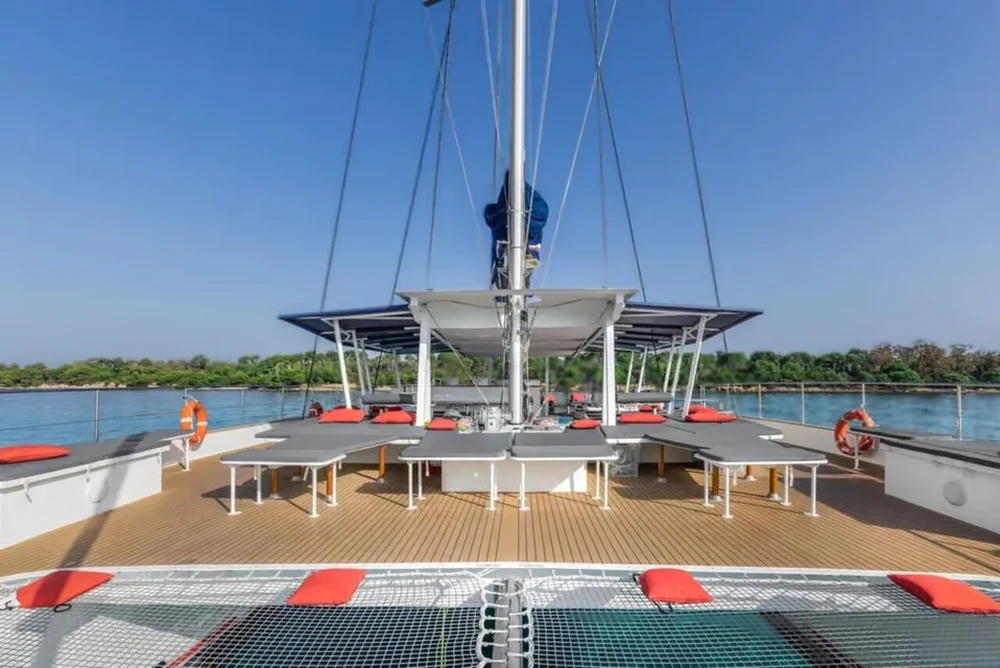 Cubierta de catamarán con mesas, redes y asientos sobre el agua