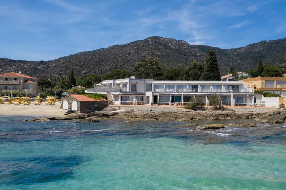 Hotel moderno frente al mar con fachada blanca y costa rocosa mediterránea