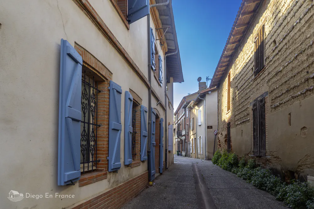 Architecture traditionnelle de Saint-Sulpice-la-Pointe avec des fenêtres à volets en bois peint.